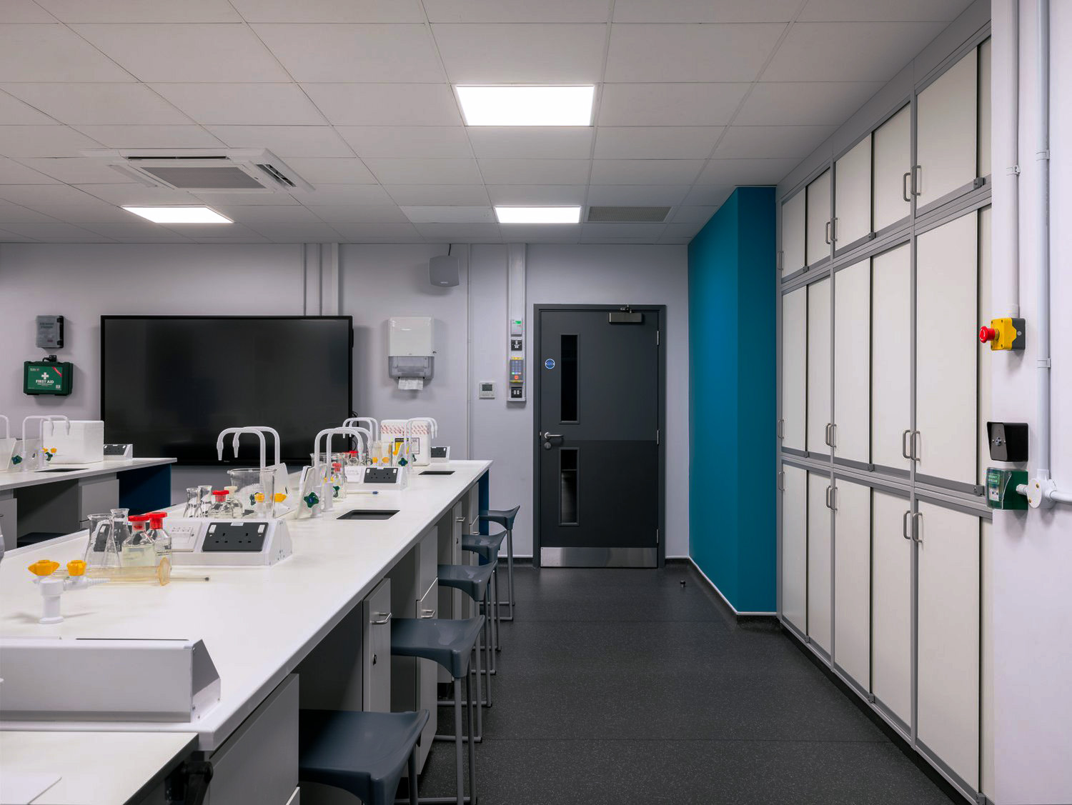 Active laboratory space with fitted laboratory furniture including mobile cabinets, wall storage, and services.